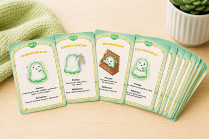 A fan of illustrated prompt cards spread on a light wood surface, with a green knitted fabric and a small potted succulent in the background.